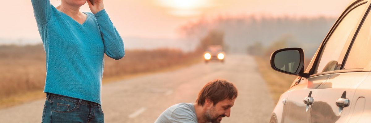 Couple repairing car flat tire on the road